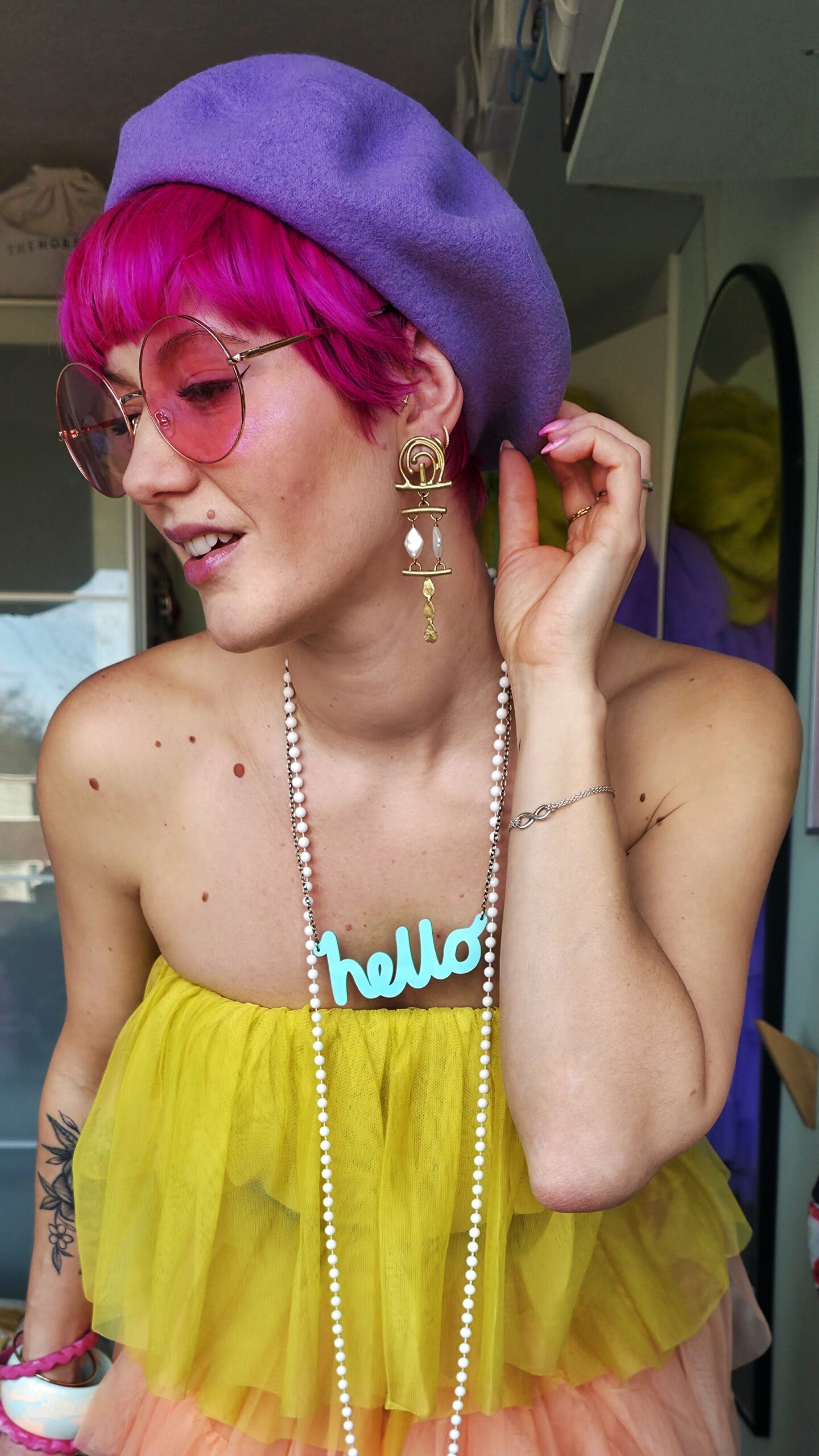 adeline wearing a purple beret, pink sunglasses, hello necklace, yelloww tulle top