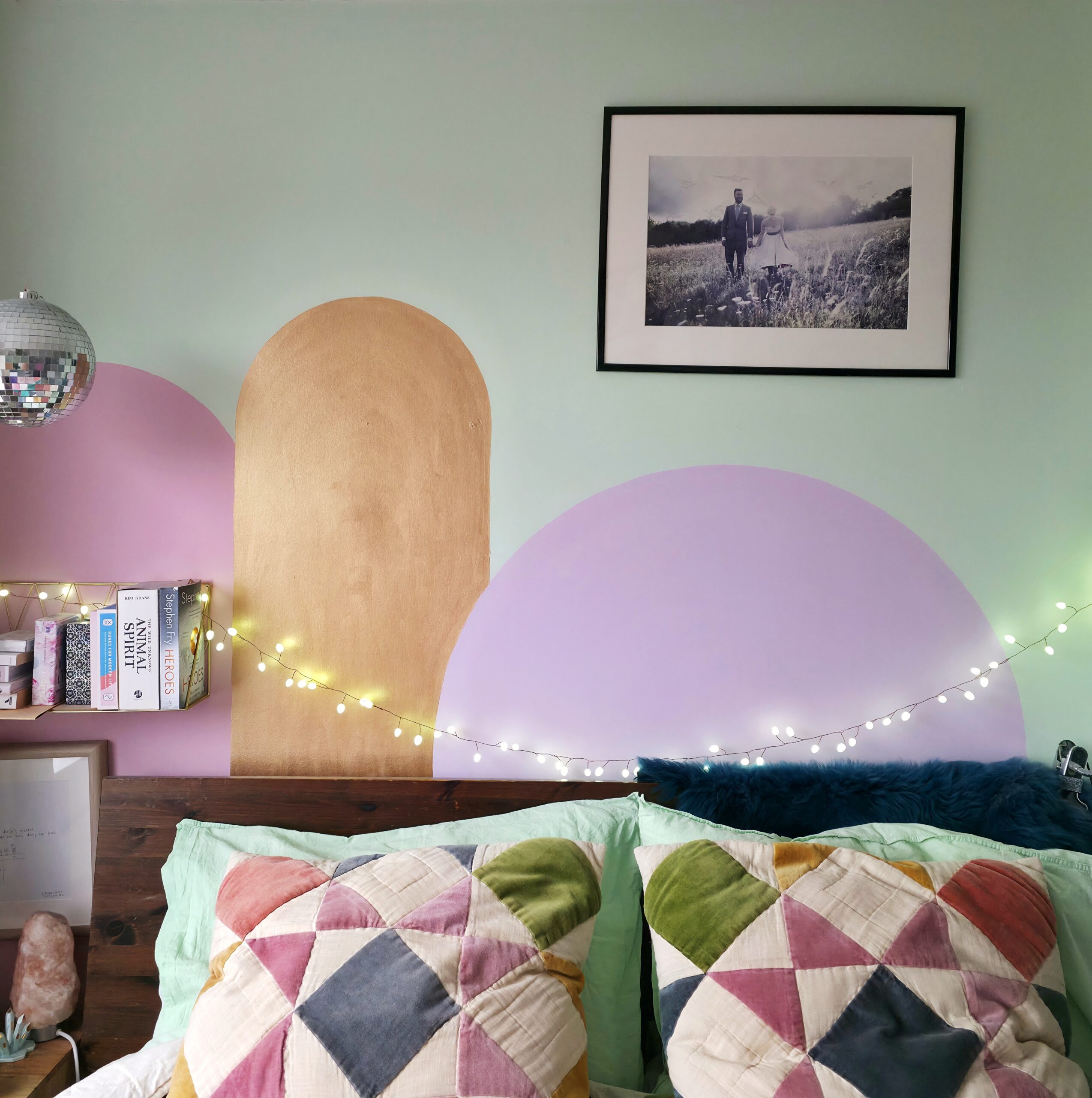 a photo of a bedroom wall which is light green, with painted arches i pink, gold and and lilac